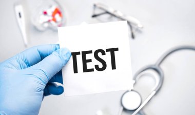 Doktorun mavi eldivenli elleri TEsT kelimesini gösteriyor. Beyaz arka planda eldivenli bir el. Tıbbi konsept. İlaç.