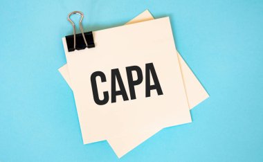 Fotokopi alanı ve ataç içeren yapışkan notlar üzerine kırmızı arkaplanda CAPA metni. Finans ve ekonomi kavramı.