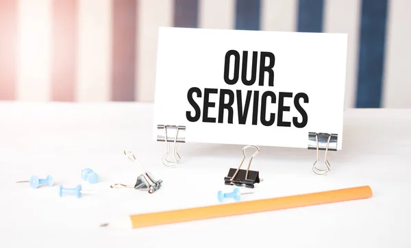 our services sign on paper on white desk with office tools. Blue and white background