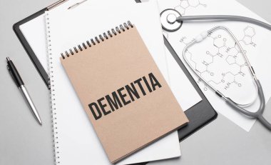 Yazıt DEMENTIA. Masanın üstünde steteskop, kalem ve tıbbi belgeler var. Sağlık hizmeti kavramı.