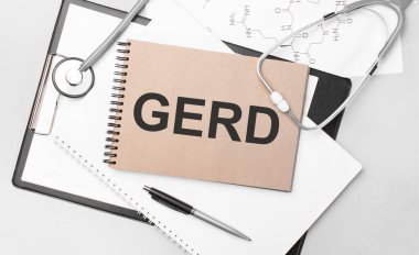 Inscription GERD. Top view of the table with stethoscope,pen and medical documents. Health care concept. clipart