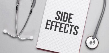 Bej bir arka planda, steteskop ve üzerinde yazı olan beyaz bir not defteri var. Tıbbi konsept