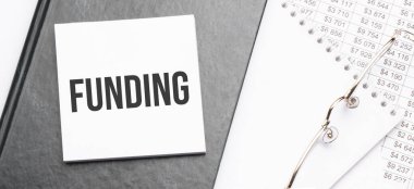 Ofis araçlarıyla not defterine metin finansmanı, finansal rapora kalem. İş ve mali konzept. Hesap makinesi ve diyagramı olan çalışma kağıdı.