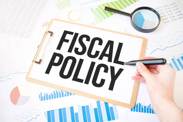 Text fiscal policy on white paper sheet and marker on businessman hand on the diagram. Business concept