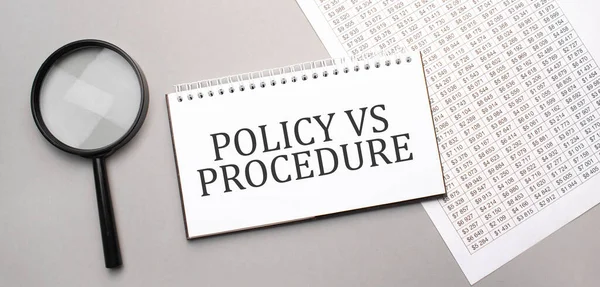 POLICY VS PROCEDURE sign in white paper notepad and magnifying glass on the grey background