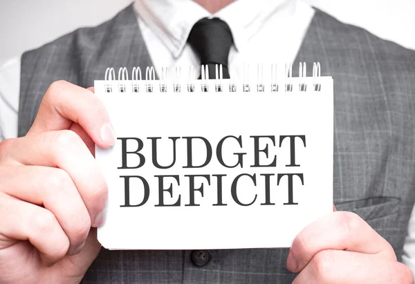 Businessman with notebook with text budget deficit . Business concept