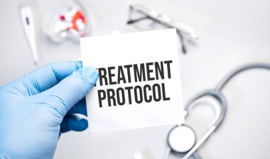 Doktorun mavi eldivenli elleri tedavi protokolünü gösteriyor. Beyaz arka planda eldivenli bir el. Tıbbi konsept. İlaç.