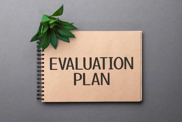 evaluation plan text on craft colored notepad and green plant on the dark background