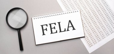 Beyaz kağıt not defterinde fela işareti ve gri arka planda büyüteç.