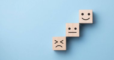 Mutsuzluktan gülümsemeye, mavi arkaplandaki duygulara uzanan ahşap bir küp çevirme..