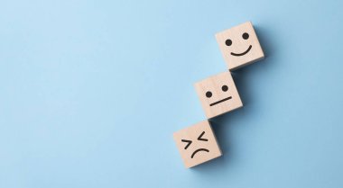 Mutsuzluktan gülümsemeye, mavi arkaplandaki duygulara uzanan ahşap bir küp çevirme..