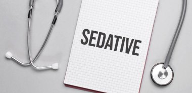 Bej bir arka planda, steteskop ve yazıt yatıştırıcılı beyaz bir not defteri. Tıbbi konsept