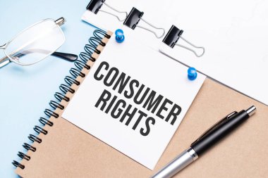 Notepad with consumer rights text on the office table with glasses, notepad and paper with clips.