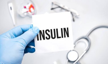 Doktorun mavi eldivenli elleri insülin kelimesini gösteriyor. Beyaz arka planda eldivenli bir el. Tıbbi konsept. İlaç.