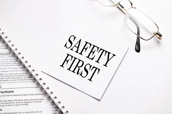 ビジネスコンセプト 灰色の背景のノートと眼鏡のための白い紙のテキストの安全性の最初のシートを持つノート — ストック写真