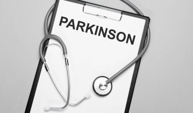 Parkinson kelimesi, steteskopun yanındaki gri arka planda beyaz kağıda yazılmıştır. Tıbbi konsept