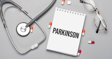 Defterde steteskop, hap ve gözlüğün yanındaki metin parkinson var..