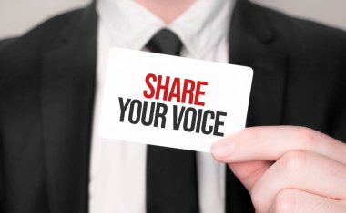 Businessman holding a card with text SHARE YOUR VOICE