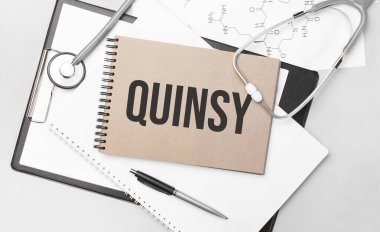 Inscription quinsy. Top view of the table with stethoscope,pen and medical documents. Health care concept.