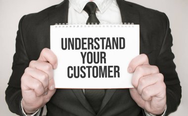 Businessman holding a notepad with text UNDERSTAND YOUR CUSTOMER