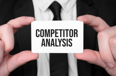 İş adamı elinde metin COMPETITOR ANALYSIS ile bir kart tutuyor