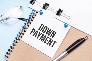 Ofis masasının üstünde gözlüklü, not defterli ve raptiyeli bir not defteri vardı..