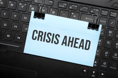 Bilgisayar klavyesindeki beyaz kağıt üzerinde CRISIS AHEAD yazıları. Kapatma iletisi.