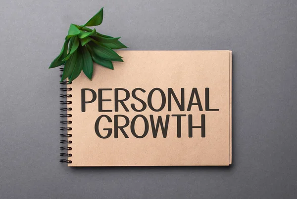 personal growth text on craft colored notepad and green plant on the dark background