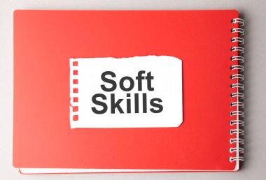 Kırmızı not defterindeki yırtık kağıt üzerinde SOFT SKILLS sözcüğü,.