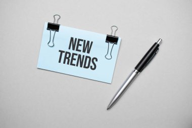 Renkli bir arka planda metin yeni trendleri, kalem ve ataçları olan bir kartvizitin üst görüntüsü. İş konsepti.
