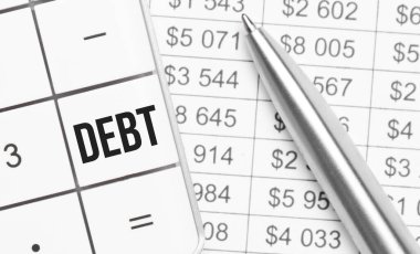 İş ve finans. Masanın üzerinde bir rapor, bir kalem ve hesap makinesi var, büyük tuşun üzerinde - DEBT