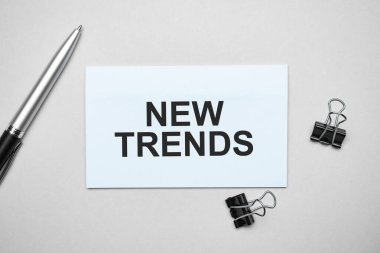 Renkli bir arka planda metin yeni trendleri, kalem ve ataçları olan bir kartvizitin üst görüntüsü. İş konsepti.