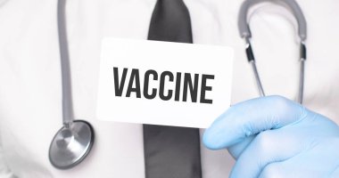 Doktor elinde bir kart tutuyor. Yazılı VACCINE, tıbbi konsept.