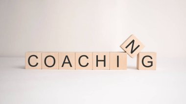 Koçluk kelimesi arka planda tahta küplere yazılır. İş konsepti