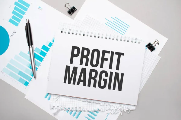 Paper plate with text PROFIT MARGIN. Diagram, notepad and blue background