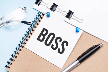 Ofis masasında gözlüklü, not defterli ve raptiyeli bir not defteri..