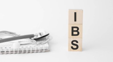 Beyaz arka planda izole edilmiş ahşap küplere yardım yazıları, tıp konsepti. Masanın yanında steteskop ve haplar var..