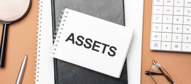 Not defterindeki varlıklar ve kahverengi arka plandaki çeşitli iş evrakları. Kahverengi gözlükler ve not defteriyle büyüteç.