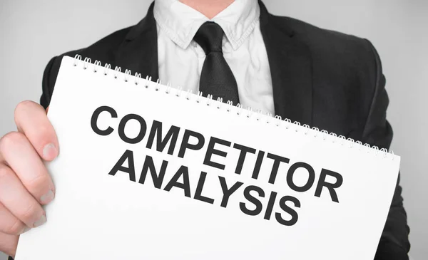 Affärsman Som Innehar Ett Kort Med Text Competitor Analysis — Stockfoto