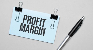 Renkli arka planda PROFIT MARGIN, kalem, ataç içeren bir kartvizitin üst görüntüsü. İş konsepti.