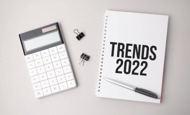 2022 kelime eğilimleri bir kalem, hesap makinesi ve raporların yanında beyaz bir arkaplanda yazılmıştır. İş konsepti