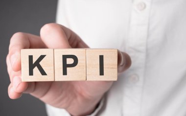 İş adamı elinde KPI metniyle tahta küp tutuyor. Mali, pazarlama ve iş kavramları