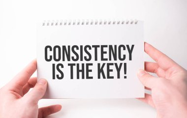 Tutarlılık, bir adamın elindeki beyaz kart kağıdına yazılan anahtar kelimedir. Beyaz kağıtta siyah harfler. İş konsepti.