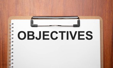 Tahta masadaki beyaz kağıt üzerinde OBJECTIVES metin