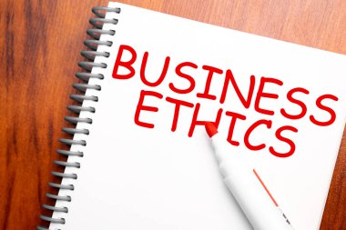 Not defterinde yazılı metin BUSINESS ETHICS, yukarıdan ofis ahşap tablosu ve kırmızı kalem, blog başlığı veya başlık resmi için konsept resmi. Yıllanmış vintage rengi görünümü.
