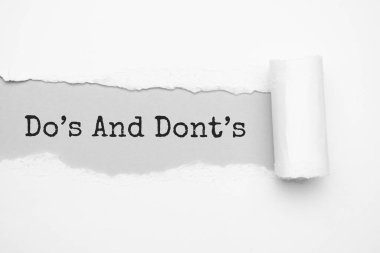 Yırtık kahverengi kağıdın arkasında görünen DO S ve DONTS metni