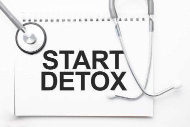 Gri steteskop ve kağıttan bir sayfa beyaz kağıt ile detoks başlat açık mavi arka plan. Tıbbi konsept.