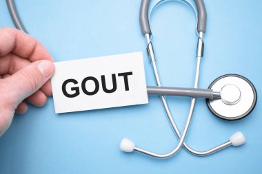 Doktorun elinde gut hastalığının yazılı olduğu bir kartvizit var. Diğeri de metni işaret ediyor..