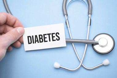 Doktorun elinde diyabet metninin olduğu bir kartvizit var. Diğer elinde de metne işaret ediyor..