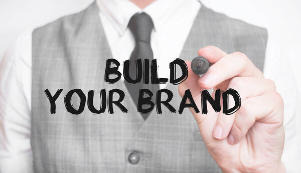 бизнесмен, пишущий слово, построит свой бренд с маркером, бизнес-концепцией